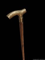 Close-up of the brass handle showing detailed floral engravings on the vintage walking cane.