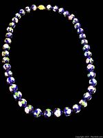 Full view of the vintage Chinese cloisonné necklace laid out flat, showing the round beads and floral design.