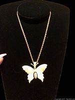 Front view of the necklace displayed on a black bust form showing the full butterfly pendant and chain.