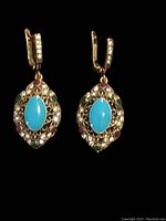 Front view of the pair of vintage style earrings showing the blue turquoise center stone and surrounding multi-colored gemstones on a brushed gold finish.