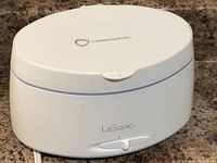 Closed view of the white Connoisseurs LaSonic ultrasonic jewelry cleaner showing single dial and logo on lid.