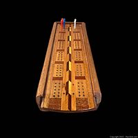 Top front view showing wooden cribbage board with detailed inlay and pegs in the holes.