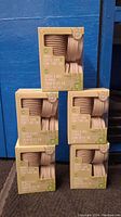 Five packages of GreenFit bamboo coffee cups stacked in a pyramid formation. Each box contains 12 cups with lids.