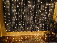 Light curtain displayed over a dark curtain, showing warm white LED lights evenly spaced in vertical strings about curtain length.