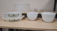 Display of all items included: large white plastic Tupperware, 2 Glasbake floral glass dishes, 4 other clear glass dishes, and 2 white milk glass mixing bowls