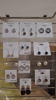 Full display of 10 pairs of earrings on metal rack, assorted designs and brands Christina C. and Exquisite C.