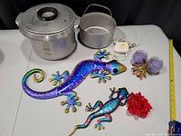 Photo showing the two metal lizard decorations, vintage stove insert pot with basket, lavender candles, vintage shaver and power adapter cable all visible.