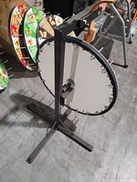 Prize wheel showing the sturdy metal base with a cross-shaped foot and a single blank spinning face with metal pins around the edge.