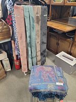 Scarves displayed on rack and one blue embroidered scarf folded, showing full lot