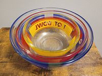 Top view showing the nested arrangement of three glass bowls with colored rim bands in blue, red, and yellow.