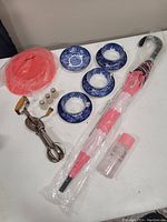 Full lot showing all items including teacups, saucers, egg beater, salt shakers, umbrella, Tupperware, and spray bottle on white surface.