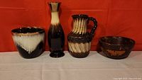 All four pottery pieces displayed side by side against orange background showing sizes and shapes.