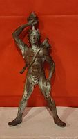 Front view of bronze archer figure with torch held high and quiver on back.