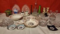 Wide view of lot contents showing various glassware, ceramics, and collectibles arranged on table.