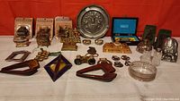 Full view of the lot arranged on red background including boxed nostalgia pencil sharpeners, glass ink wells, decorative metal items, and pewter plate