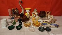 Wide view of the vintage collectibles lot showing various ceramic and glass items, figurines, dishes, and a tall ceramic swan figurine.