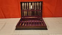Full view of 38 pieces silverware set inside the wooden chest with purple velvet lining.