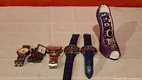 Overall photo of all wristwatches and purple shoe ring holder with rings inside.