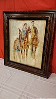 Full view of the framed oil painting showing three riders on horses in a carved wooden frame.