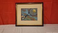 Framed pastel drawing showing the entire piece with tennis racket and ball on a colorful background.