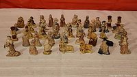 Overview of 43 small ceramic Wade figurines in various poses and characters, arranged on a flat surface