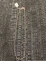 Full view of the 16-inch silver beaded necklace laid flat on a textured black and white surface.