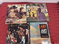 Four artbooks arranged on a red surface, displaying their colorful cover art featuring impressionism, baroque, and modern art themes.