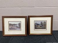 Two framed landscape prints by Bill Saunders placed side by side, showing rural lake scenes with houses and trees.