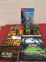 Photo of 5 books arranged on a red cloth, including titles about Guggenheim Museum Bilbao and Rome