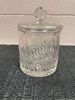 Crystal jar with lid displayed upright on a dark fabric surface showing the intricate swirling pattern and faceted lid knob.