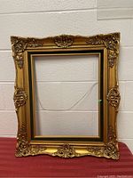 Full view of gold-colored vintage wooden picture frame with ornate corners and edges, showing its size and shape