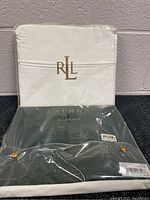 White twin flat sheet with RLL embroidery and green Ralph Lauren Classic 350 sheet in original packaging.