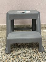 Side view of gray 2-step plastic step stool showing sturdy build and textured steps