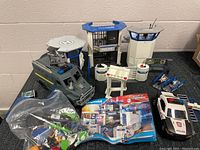 Full view of the Playmobil Police Headquarters set with prison, police vehicles, fences, accessories and instruction manual displayed on the floor.