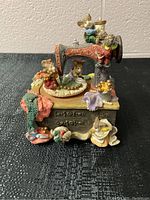 Front angled view showing sewing machine music box and mouse figurines on wooden dresser base with sewing accessories.