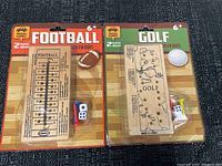 Photo of both wooden travel games in original packaging showing football and golf themes with dice and pegs.