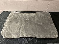 Folded grey weighted blanket with soft plush fabric and sewn segmented design for weight distribution.