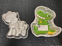 Photo showing both the dinosaur and My Little Pony shaped cake pans from the front, highlighting their distinct shapes and designs.