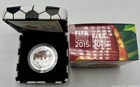 Colorful close-up of silver coin featuring FIFA Women's World Cup soccer players and crowd, housed in a protective capsule inside a soccer ball-patterned box with certificate.