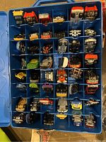 Top-down view of allocated slots inside the blue carrying case showing 48 vintage Hot Wheels cars arranged in individual compartments.