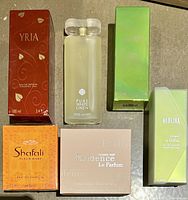 Photo of all six perfume bottles and boxes arranged together showing Syria, Pure White Linen bottle, Evidence, Shafali, and two Neblina boxes.