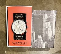 Watch in original box showing face and chronograph subdials, date window, and brand name on dial.