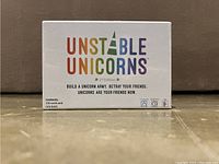 Front of the Unstable Unicorns 2nd Edition card game box showing colorful title and edition details, with contents info.