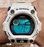 Watch worn on wrist showing digital display of time 7:39:01, day SAT, date 1-18, tide and moon phase visible.