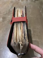 Side view of red vinyl record carrying case holding 28 records with plastic sleeves