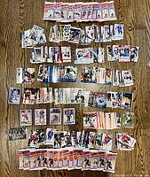 Large assortment of loose hockey sports cards and unopened packs laid on a wooden surface