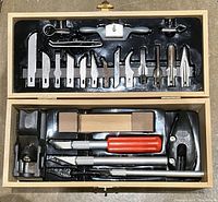 Top and bottom compartments of the wooden case showing multiple hobby craft tools: blades, gouges, sanders, planes, knives with handles.