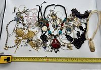 Photo overview of all jewelry items spread on white surface with measuring tape for scale.