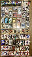 Top view of a layout of NHL hockey cards with jersey memorabilia, rookies, holographic and rare cards spread on a wood floor.