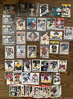 Overview photo of hockey card collection laid out on wooden floor showing different NHL players, teams, and card designs